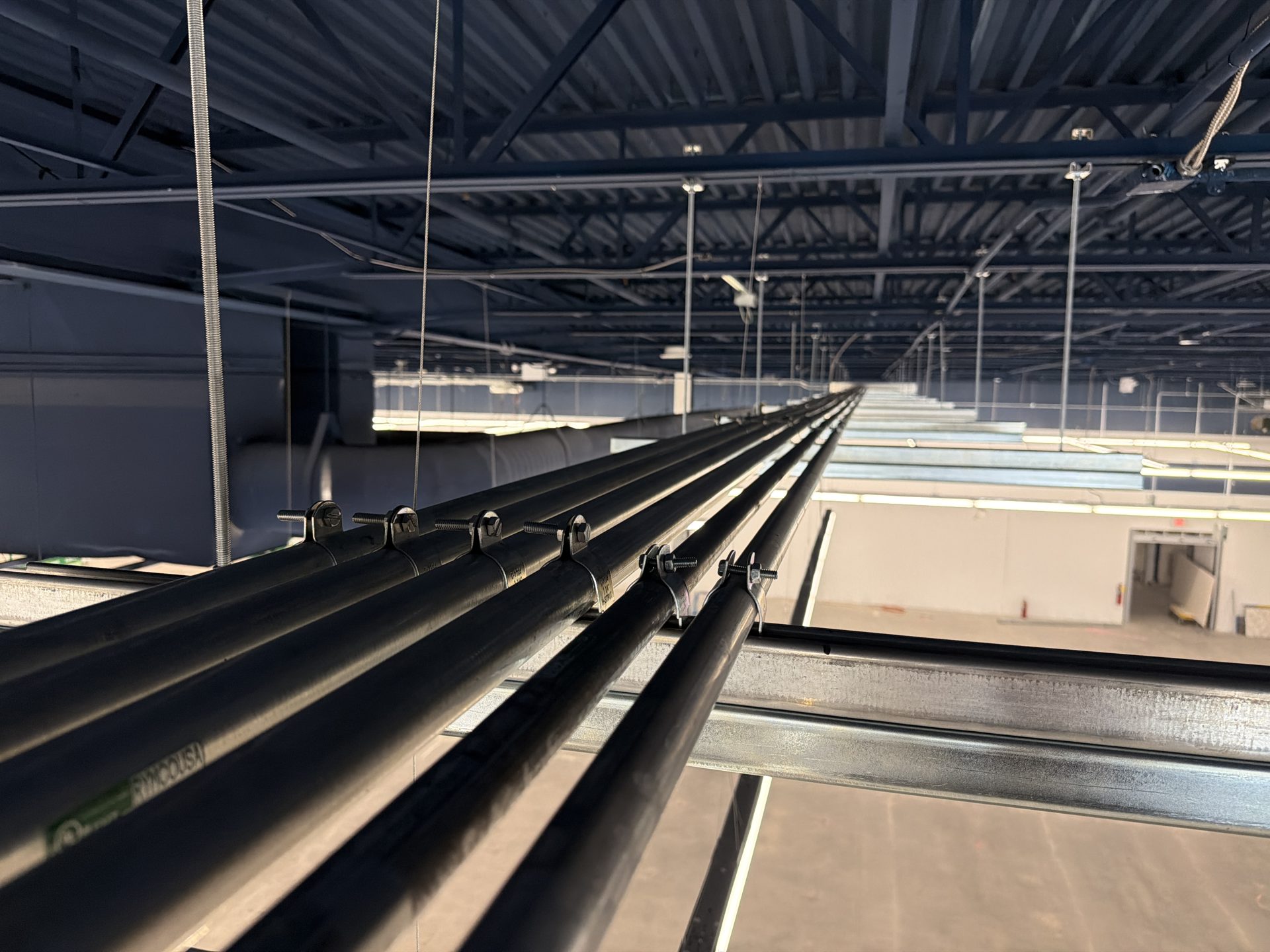 Overhead feeder conduit runs in a commercial building