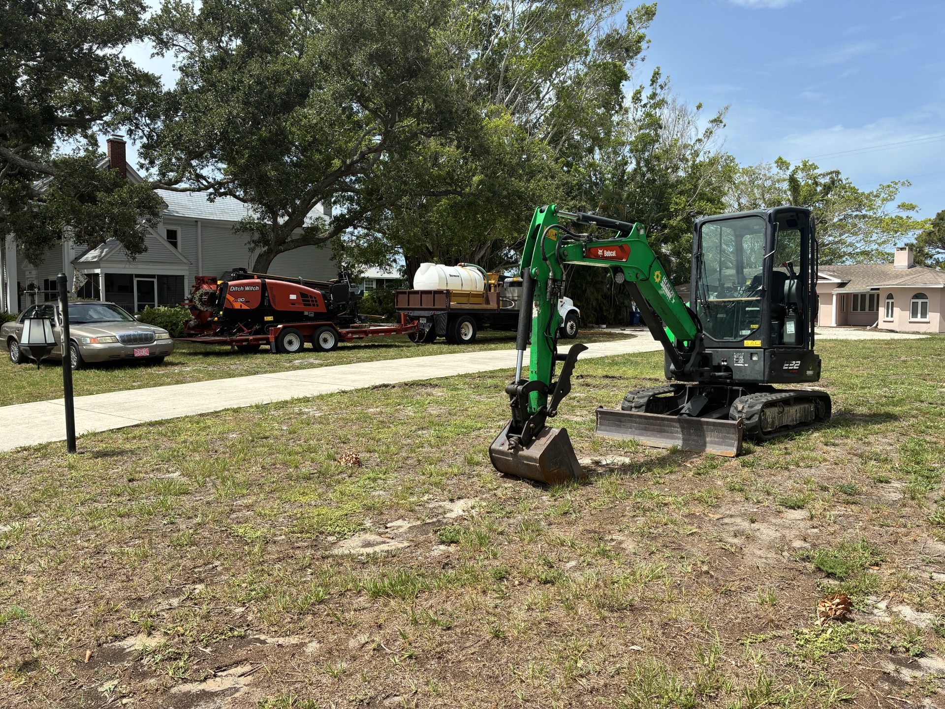 Mini excavator trenching for an underground electrical service at a residence